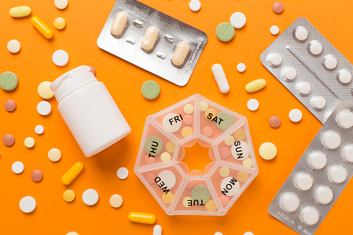 Daily pill box with medications on color background, top view