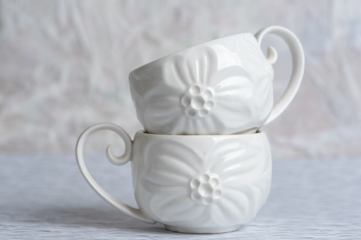 White delicate and elegant coffee cups on a light background