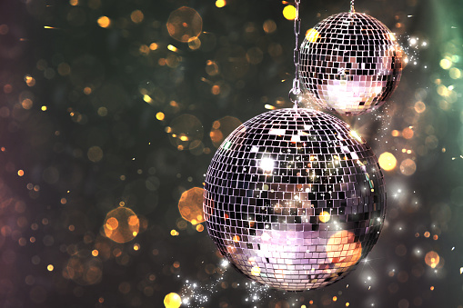 Shiny disco balls on dark background with blurred lights, space for text. Bokeh effect