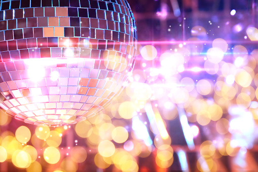 Shiny disco ball on bright background with blurred lights, bokeh effect