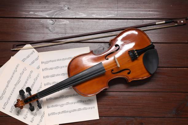 istock Violin, bow and music sheets on wooden table, top view 1890521219