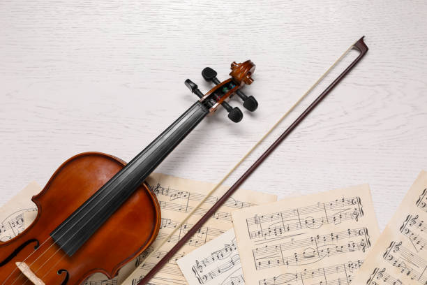 istock Violin, bow and music sheets on white wooden table, top view 1890523326