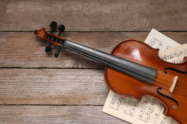 istock Violin and music sheets on wooden table, top view. Space for text 1890523509