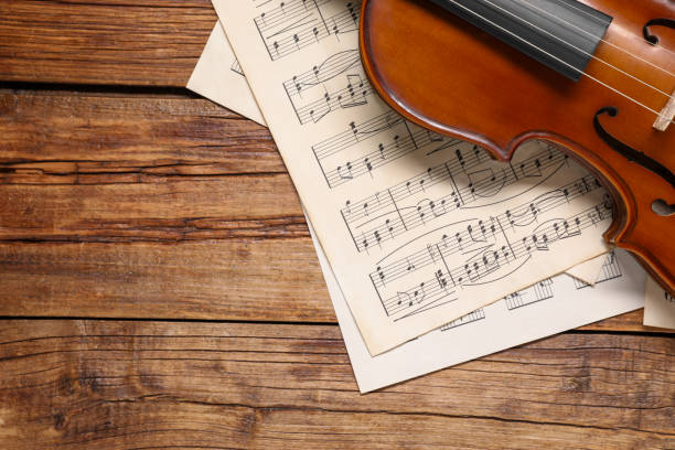 istock Violin and music sheets on wooden table, top view. Space for text 1890524894