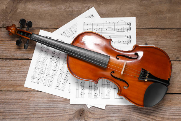 istock Violin and music sheets on wooden table, top view 1890525399