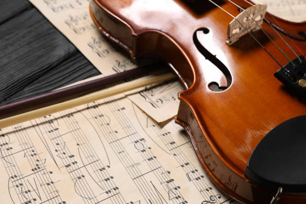 istock Violin, bow and music sheets on black wooden table, closeup 1890525918