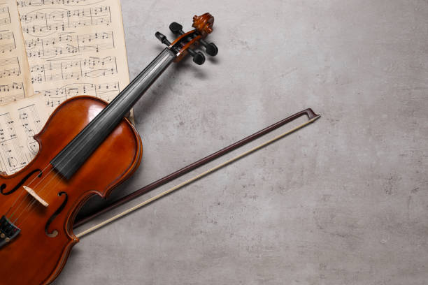 istock Violin, bow and music sheets on grey table, top view. Space for text 1890525921