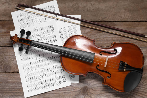 istock Violin, bow and music sheets on wooden table, top view 1890525923