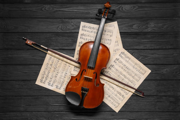 istock Violin, bow and music sheets on black wooden table, top view 1890526433