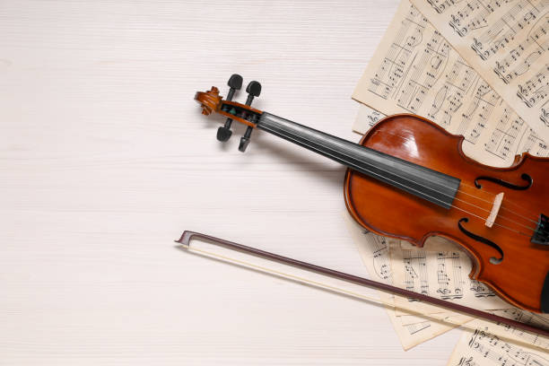 istock Violin, bow and music sheets on white wooden table, top view. Space for text 1890526443