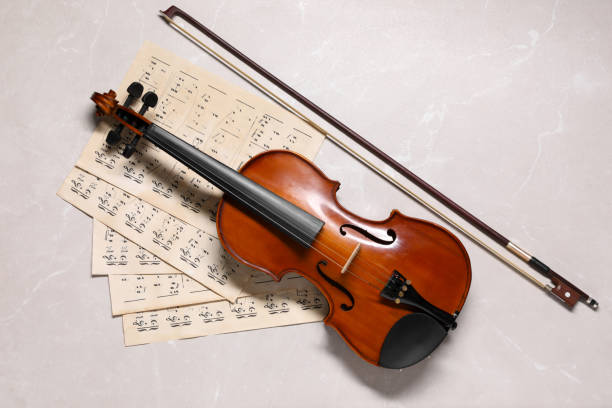 istock Violin, bow and music sheets on grey marble table, top view 1890526958