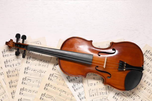 istock Violin and music sheets on white wooden table, top view. Space for text 1890526962