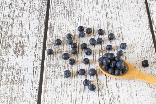 istock Blueberries on a Spoon lying on Blue Wood Background 1890549103
