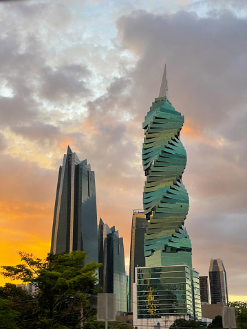 Spectacular architecture of famous spiral building under colourful sunset clouds. Stunning view of city with high-rise skyscrapers in modern financial district of Panama City in golden sunset light.