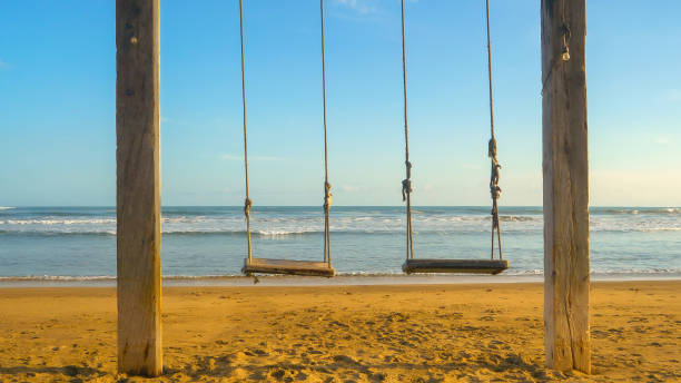 istock CLOSE UP: An empty beach swing overlooking the waves in beautiful morning light 1890561262