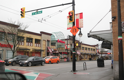 Vancouver, Canada - December 21, 2023: Drivers wait along Commercial Drive at East 1st Avenue. Retailers and independent restaurants line The  Drive neighbourhood of East Vancouver. Winter morning with overcast skies.