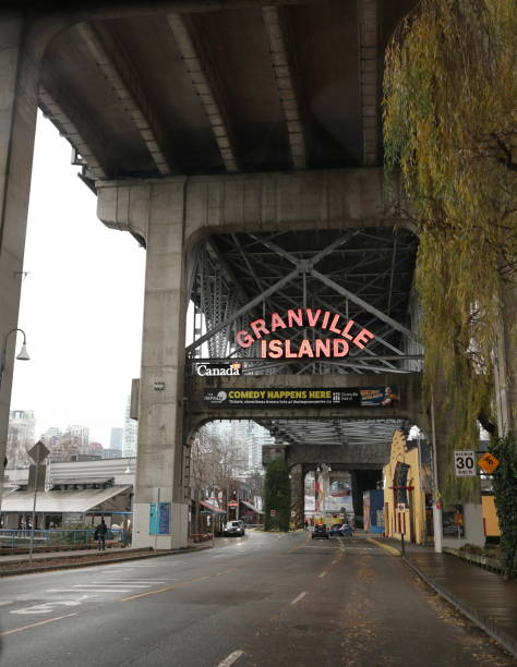 Granville Island Entrance, Vancouver, Canada Vancouver, Canada - December 21, 2023: The illuminated Granville Island sign marks the entrance above Anderson Street. The overhead Granville Street Bridge and Highway 99 carry traffic between the Fairview neighbourhood and downtown district. Winter morning with overcast skies. granville island stock pictures, royalty-free photos & images