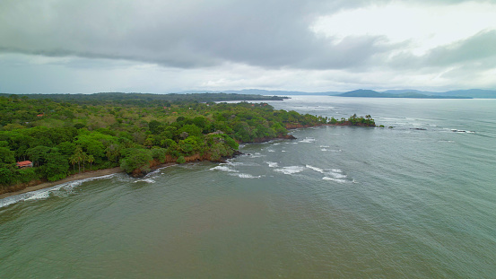 AERIAL: Fickle rainy season weather along beautiful tropical coastline in Panama. Empty exotic sandy shore by Pacific Ocean before weather worsening. Rolling rain clouds above picturesque landscape.
