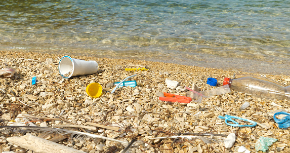 CLOSE UP: Pebble beach polluted by plastic waste washed up by the Adriatic Sea. Sad sight for an all too common occurrence on beautiful seashores. Coastal landscape where garbage remains accumulate.