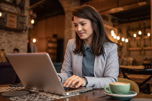 Portrait of a beautiful business woman sitting in a coffee shop and using a laptop