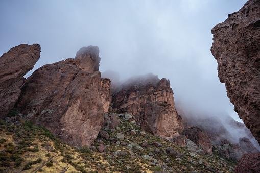Morning fog hangs over the rugged landscape of the Superstition Mountains after a winter storm in Lost Dutchman State Park in Apache Junction, AZ