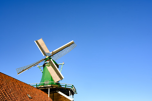 In Zaanse Schans, Netherlands a historic wooden windmill stands out against a clear blue sky on a sunny winter day.