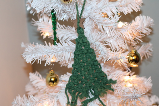 Crochet green ornament on white Christmas tree.