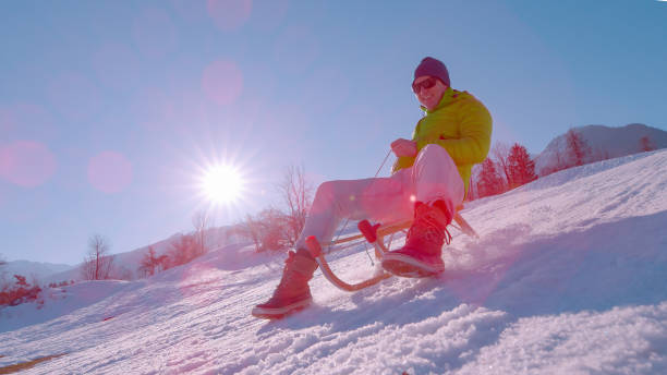 istock CLOSE UP, LENS FLARE: Active young guy enjoys a sleigh ride on winter holidays 1890647472