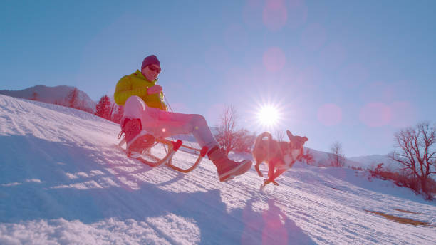 istock CLOSE UP, LENS FLARE: Guy sledding down the snowy hill on a sunny winter day 1890647473