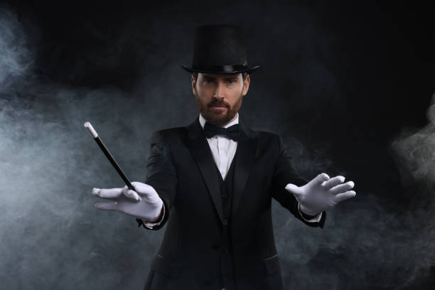 istock Magician holding wand in smoke on black background 1890653177