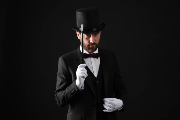 istock Magician in top hat holding wand on black background 1890653693