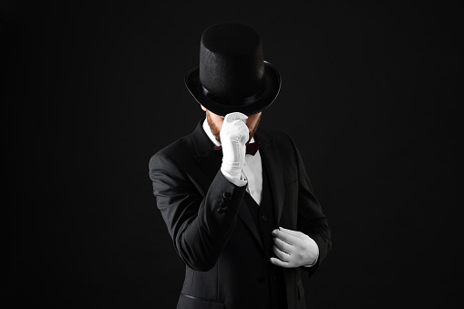 Magician in top hat on black background