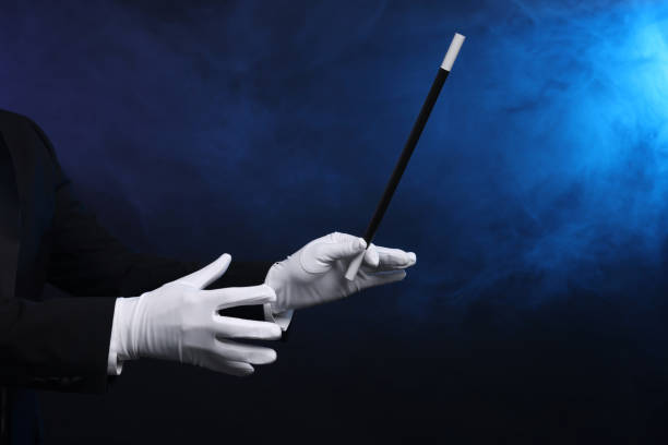 istock Magician holding wand in smoke on dark background, closeup. Space for text 1890654721