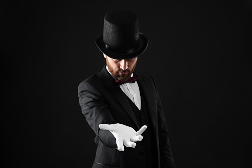 Magician in top hat on black background