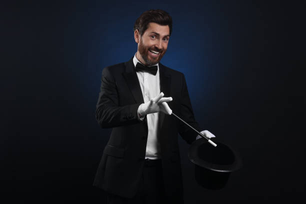 istock Happy magician showing magic trick with top hat on dark blue background 1890658365