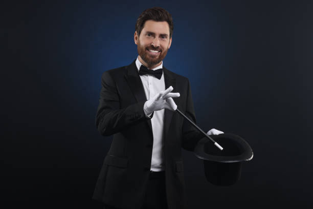 istock Happy magician showing magic trick with top hat on dark blue background 1890658908