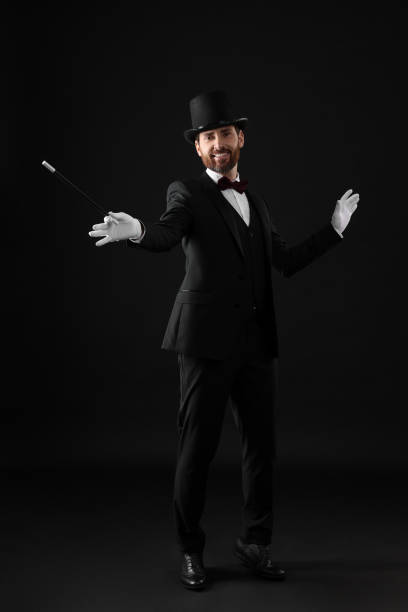 istock Happy magician in top hat holding wand on black background 1890660483