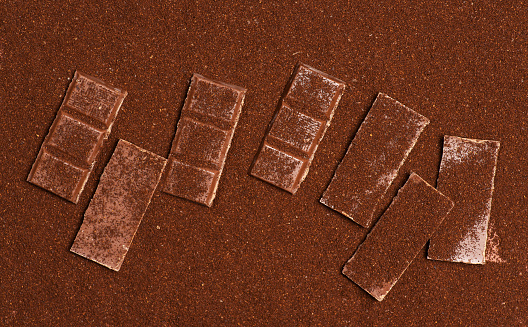 Cocoa and chocolate powder background, with milk chocolate bars