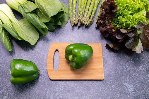 Top View Assortment Of Fresh Organic Vegetables, Green Bell Pepper On Cutting Board On Table. Asparagus Plant, Bok Choy, Red Leaf Lettuce. Healthy Bio Food, Longevity Diet. Horizontal Plane. Flatly