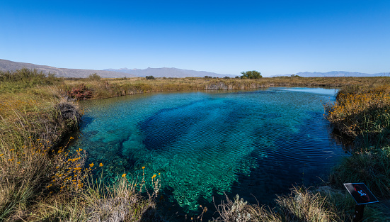 Amazing landscape with a lake and river in the middle of the desert with shades in the water of blue and turquoise green, mountains are distinguished, and the wide desert. Poza Azul, Cuatrociénegas.