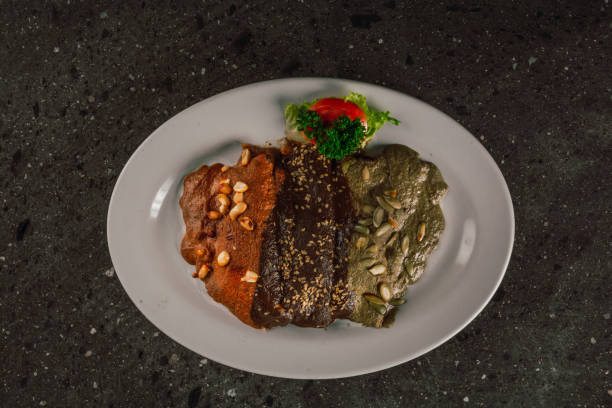 istock Enmoladas de encacahuatado, mole negro, pipian served on the same white plate, stuffed with chicken. 1890889831