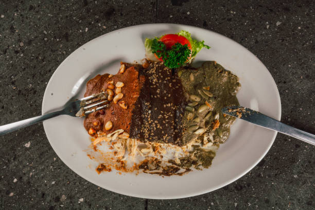 istock Woman hand cutting enmoladas de encacahuatado, mole negro, pipian served on the same white plate, stuffed with chicken. 1890891879