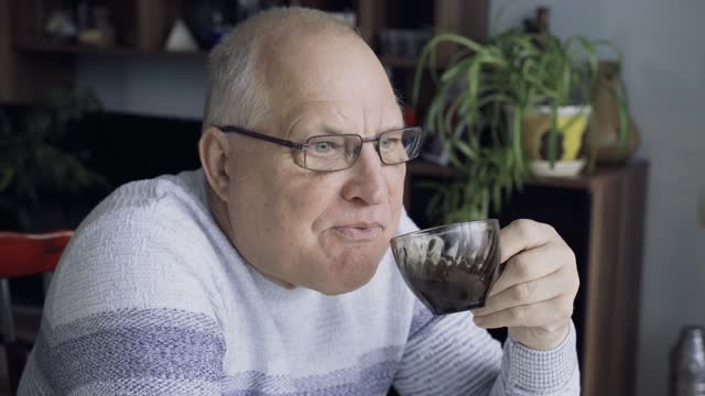 An elderly man drinks tea in the room