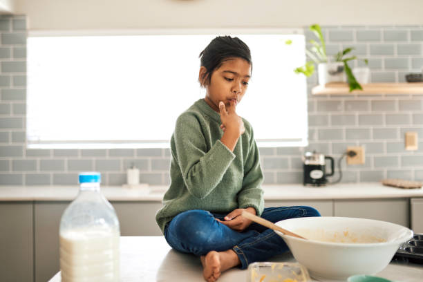 istock Young Girl Sitting on Kitchen Counter Licking Fingers 1890910841
