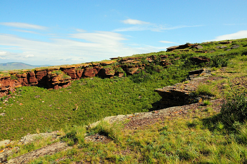 The remains of an ancient stone structure on the top of a high hill on a warm summer morning. Mountain range Chests, Khakassia, Siberia, Russia.