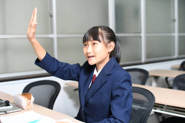 asiatische studentin hebt die hand während des unterrichts im klassenzimmer - elementary student classroom education elementary school building stock-fotos und bilder