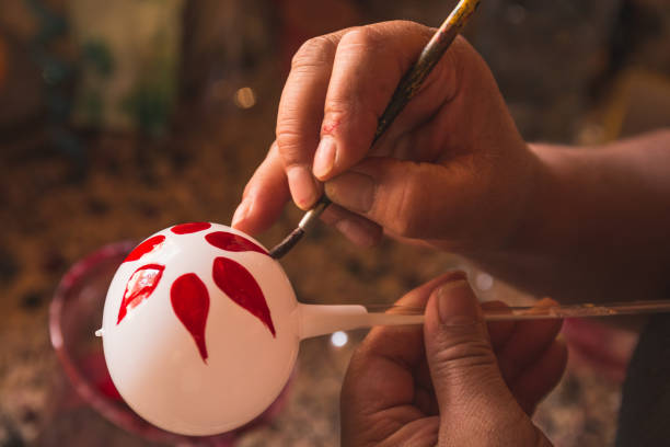istock Craftsman painting Christmas spheres in his workshop in different colors, using acrylic paint, diamond paint to give texture and different figures. 1891000149