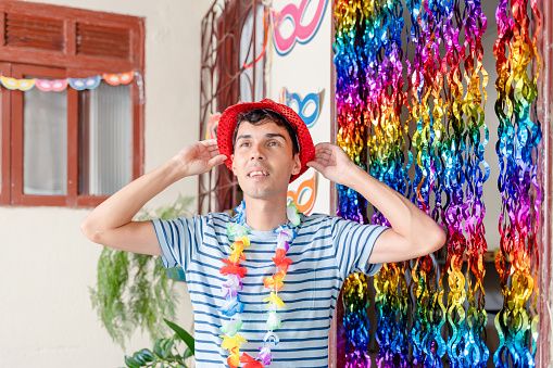 Joyful Brazilian man, dressed for Carnival, smiles in a festively decorated home. Capturing the vibrant spirit of Carnival celebration with happiness.