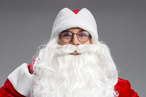 Closeup portrait of funny happy Santa Claus looking at camera isolated on gray background. Marry Christmas concept