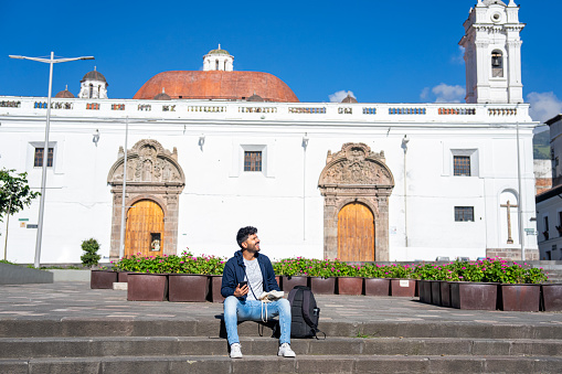 Wide full length view of young Latin man enjoying the view while sightseeing in Plaza de Santa Clara, Quito, Ecuador